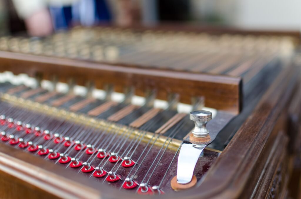 Detailed view of a dulcimer musical instrument showcasing its strings and knobs indoors.
